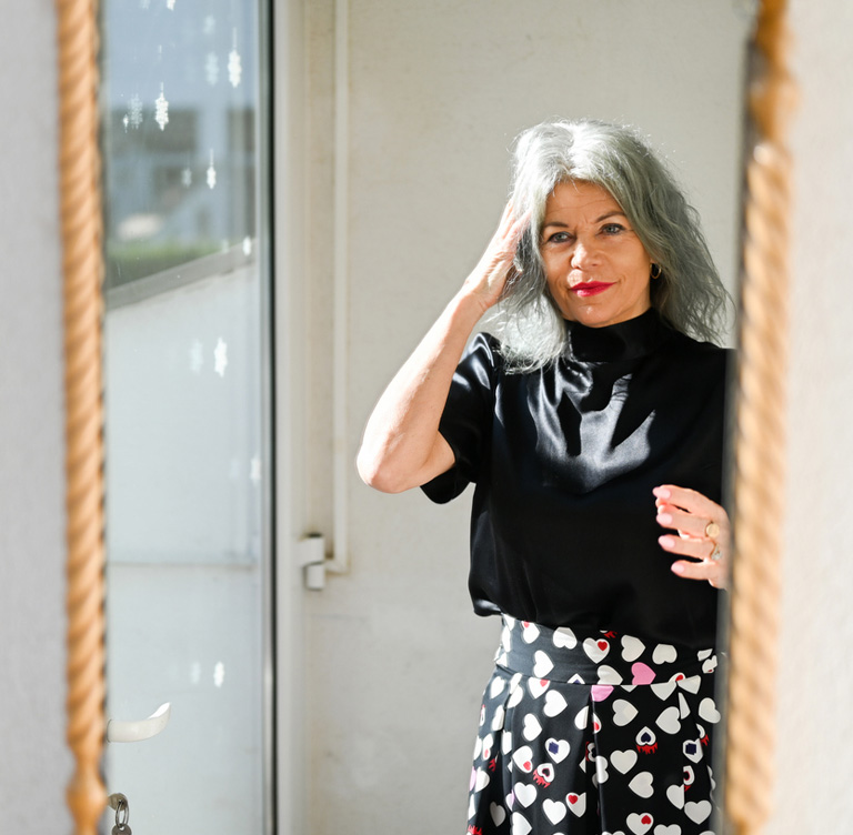 a woman standing in front of a mirror posing for the camera