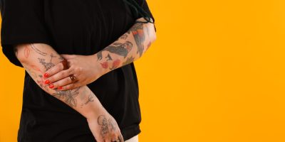 Person covering a forearm tattoo with their hand, representing a tattoo removal consultation at a Tuscaloosa medspa.