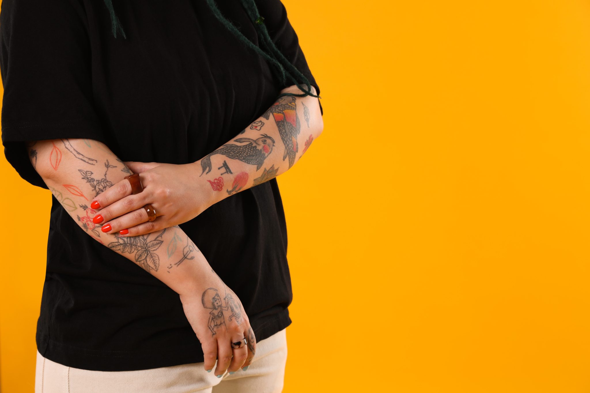 Person covering a forearm tattoo with their hand, representing a tattoo removal consultation at a Tuscaloosa medspa.
