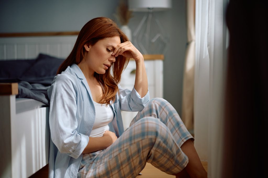Woman holding her lower stomach while experiencing symptoms of PMOS. 
