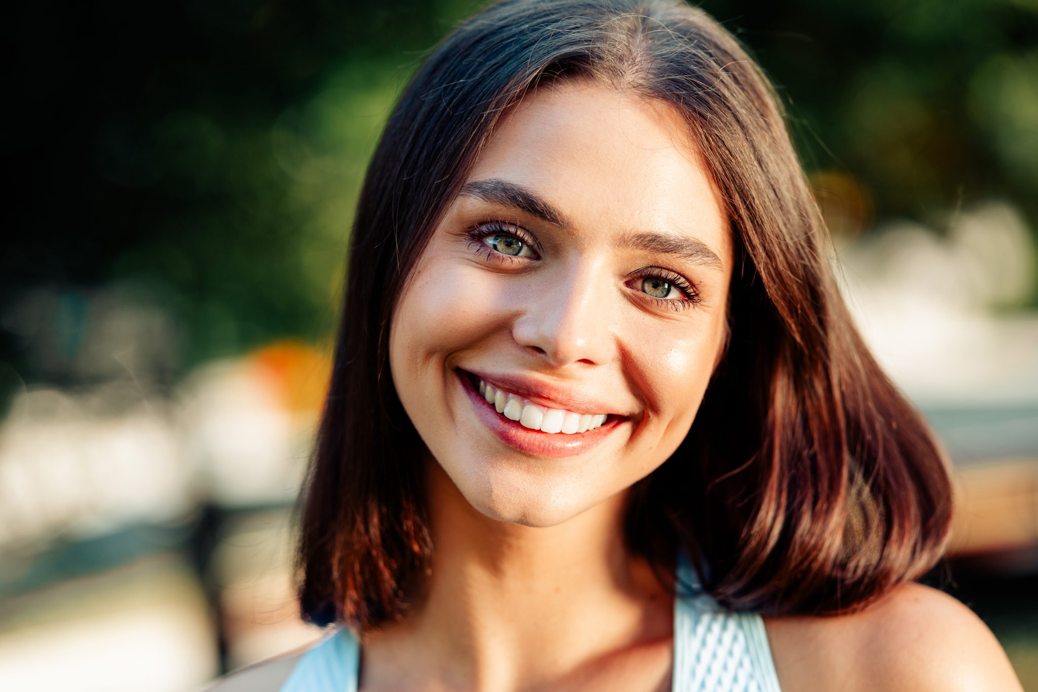 Young woman with glowing skin smiling outdoors in summer, representing pre-event skin treatments at a Tuscaloosa medspa.